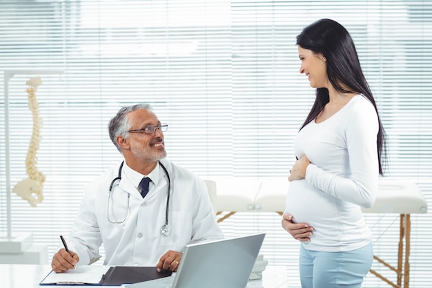 Mujer embarazada interactuando con el médico en la clínica durante el chequeo de salud