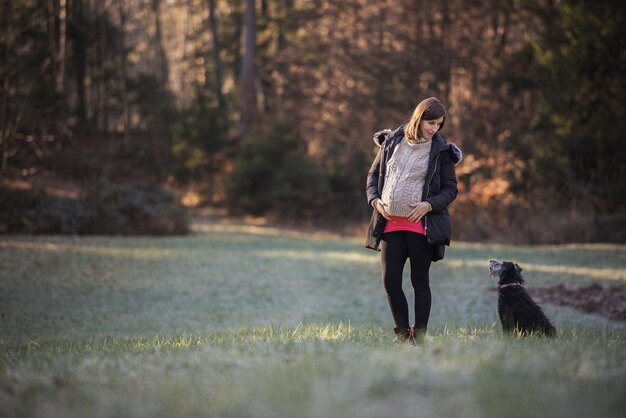 Mujer embarazada joven afuera con su perro