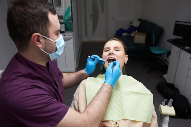 Mujer embarazada joven caucásica en la silla del dentista con la boca abierta en el chequeo en la clínica dental