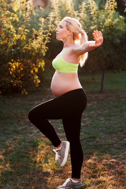Foto mujer embarazada joven que ejercita al aire libre.