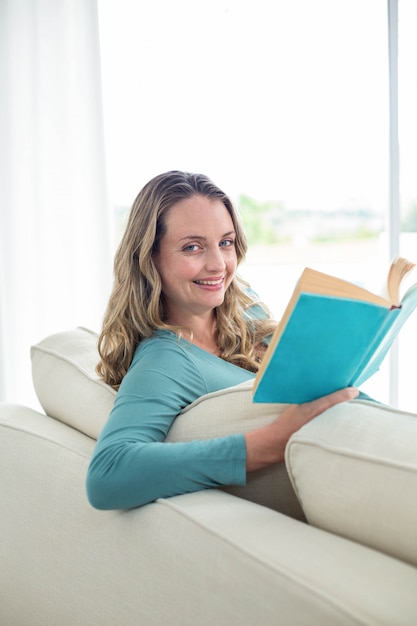 Mujer embarazada leyendo un libro en el sofá