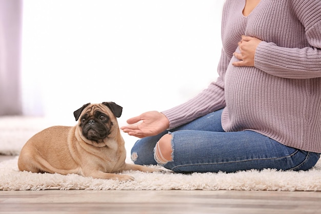 Mujer embarazada con lindo perro en casa Amistad entre mascota y dueño
