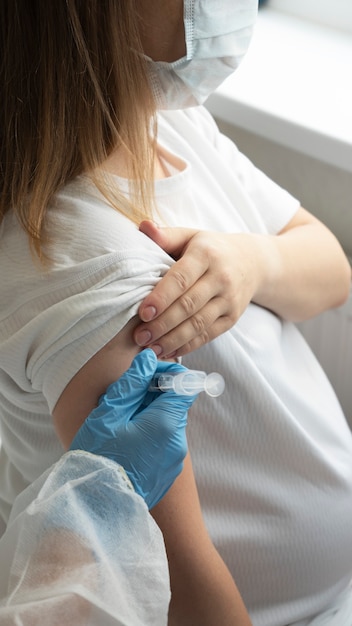 Mujer embarazada con la mano del médico para la vacunación enfermera vacunando a la joven embarazada