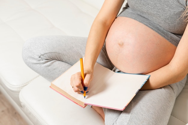Mujer embarazada manos escribiendo algo en un libro