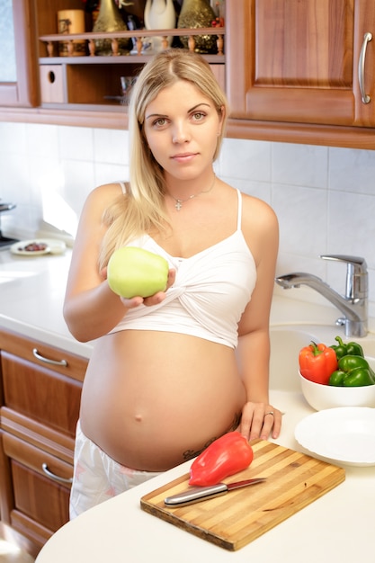 Mujer embarazada con manzana verde y sonriendo