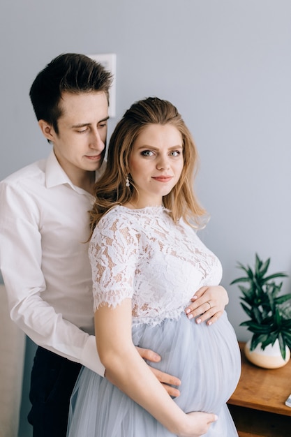 Mujer embarazada, con, marido, delante de la ventana