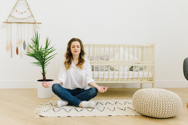 Mujer embarazada meditando y teniendo en cuenta en la guardería