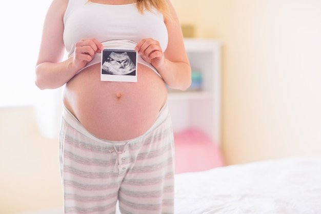 Mujer embarazada mostrando ecografías