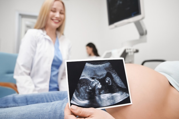 Mujer embarazada mostrando rayos x del futuro bebé.