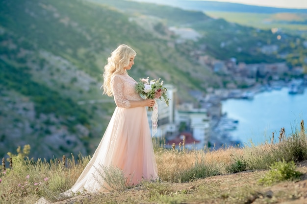 Mujer embarazada en la naturaleza. Hermosa mujer futura madre en vestido largo blanco al aire libre