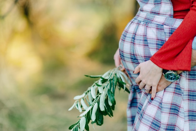 mujer embarazada en la naturaleza con una rama de olivos