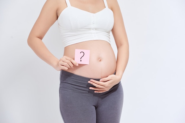 Mujer embarazada con una nota adhesiva, que dibuja un signo de pregunta, en su vientre