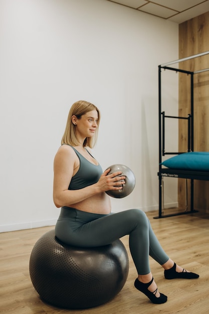 Mujer embarazada pilates ejercicio anillo mágico con fitball