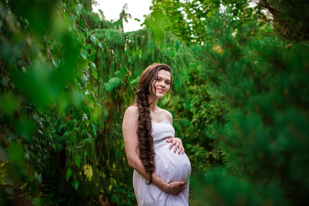 Mujer embarazada posando en un jardín verde