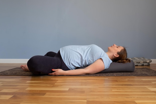 Mujer embarazada practicando yoga acostada en el ejercicio de mariposa reclinada supta baddha konasana pose