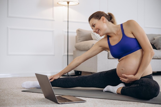 Mujer embarazada practicando yoga en casa