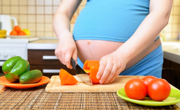 Mujer embarazada preparando una comida saludable en la cocina