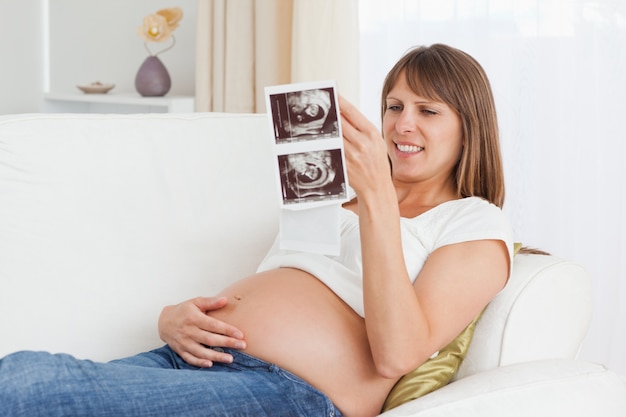 Mujer embarazada que mira el ultrasonido de su bebé