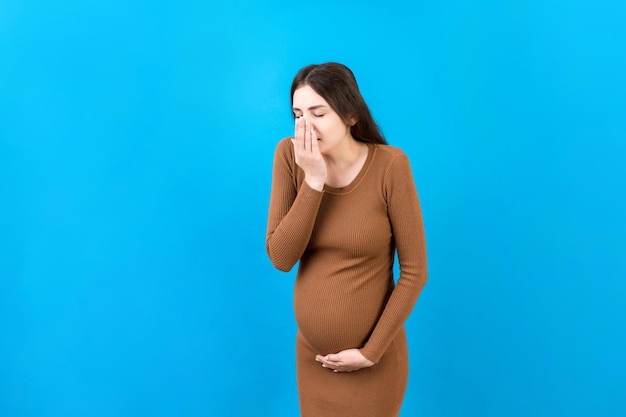 Mujer embarazada que sufre de toxicosis Toxicosis del embarazo Mujer embarazada que se siente enferma con náuseas de pie sobre fondo aislado de color Espacio libre