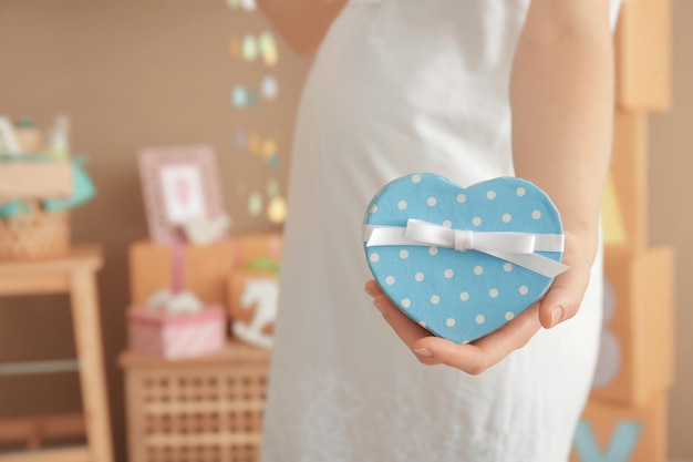 Mujer embarazada con regalo en la fiesta de baby shower en el interior