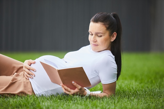 Mujer embarazada relajante con libro