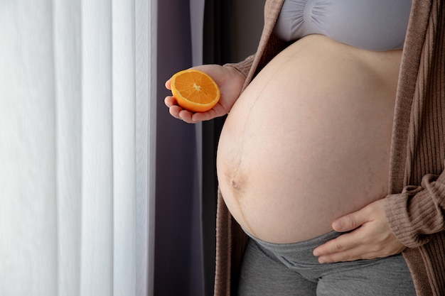 Mujer embarazada con rodajas de fruta naranja.