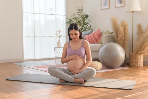 Mujer embarazada sana haciendo ejercicio y haciendo meditación de yoga prenatal