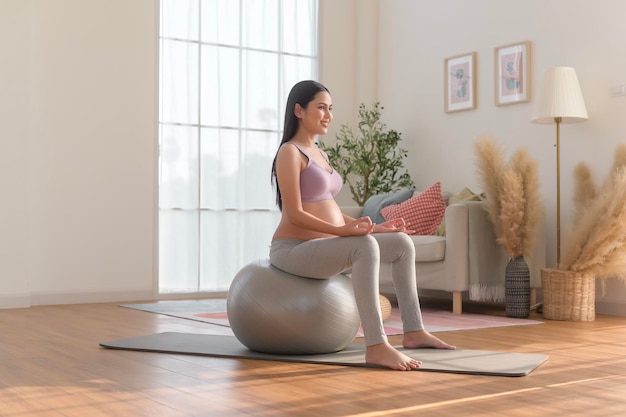 Mujer embarazada sana haciendo ejercicio y haciendo meditación de yoga prenatal