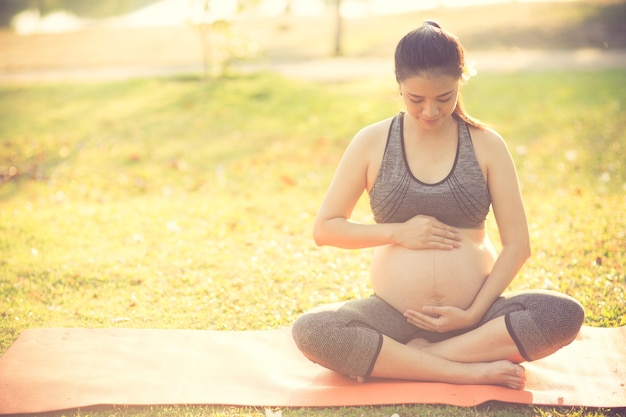 mujer embarazada sana haciendo yoga en la naturaleza al aire libre