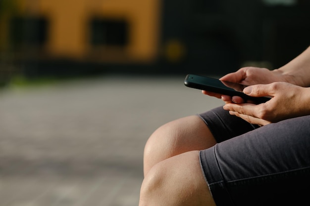 Mujer embarazada sentada en un banco sosteniendo un teléfono