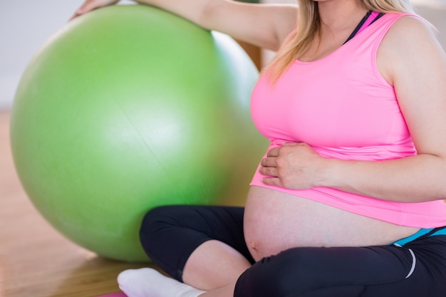 Mujer embarazada sentada con pelota de ejercicios