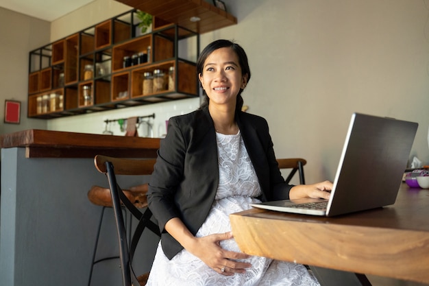 Mujer embarazada sentada sola cuando usa la computadora portátil