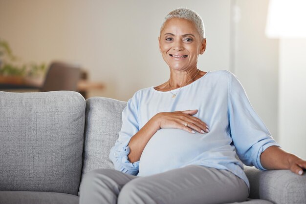 La mujer embarazada sonríe y se relaja en el sofá en la sala de estar para la atención prenatal de la salud del bebé y el apoyo de la nueva madre