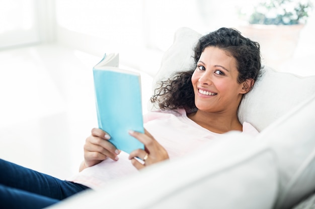 Mujer embarazada sonriendo mientras lee el libro