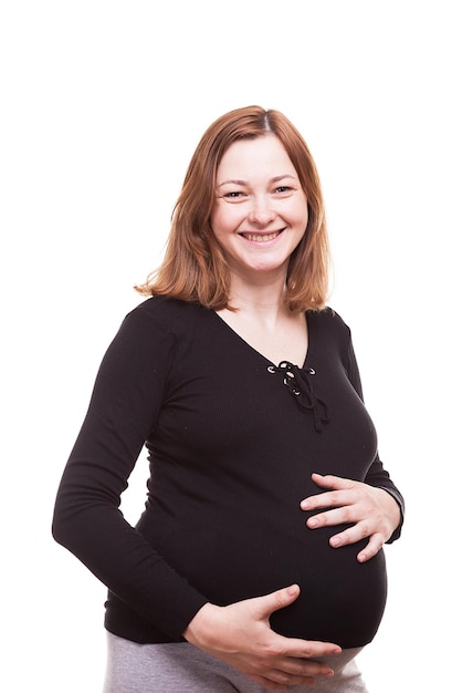 Mujer embarazada sonriente aislada sobre fondo blanco en la foto de estudio