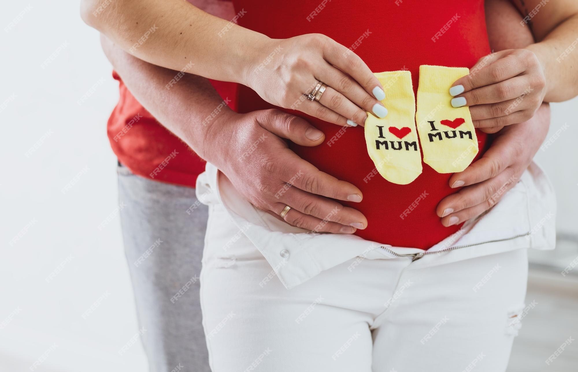 Mujer embarazada sosteniendo calcetines de bebé junto a su vientre embarazado ropa de bebé cuidado prenatal materno concepto de expectativa de bebé de embarazo de maternidad | Foto