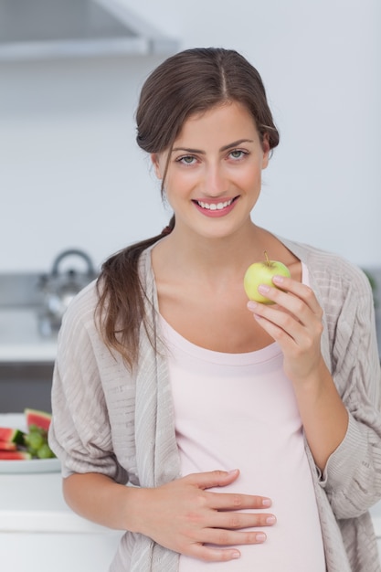 Mujer embarazada sosteniendo una manzana verde