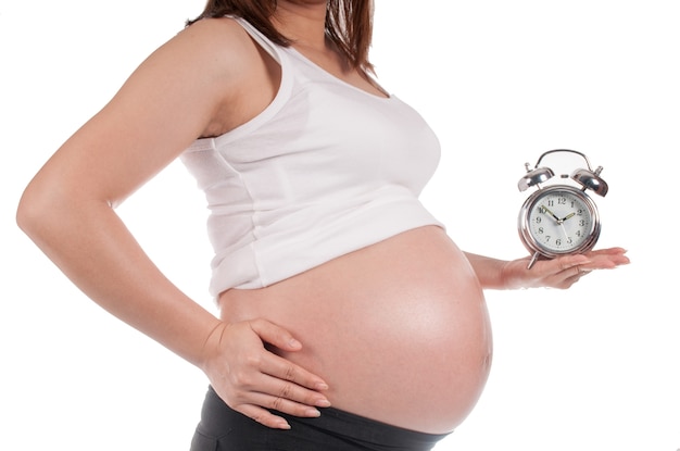 Mujer embarazada sosteniendo un reloj esperando el nacimiento