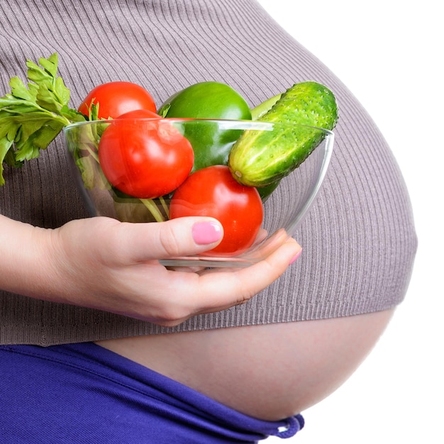 Mujer embarazada sosteniendo verduras frescas