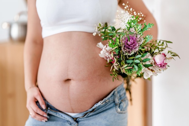 Una mujer embarazada sostiene hermosas flores Concepto lindo embarazo saludable Maternidad Día de la Madre