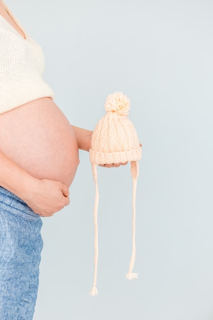 Mujer embarazada sostiene tejida cerca de su vientre esperando el nacimiento del niño