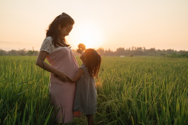 Mujer embarazada con su hija disfrutando al aire libre