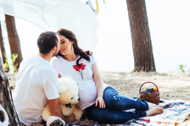 Mujer embarazada con su marido en el picnic. Feliz co