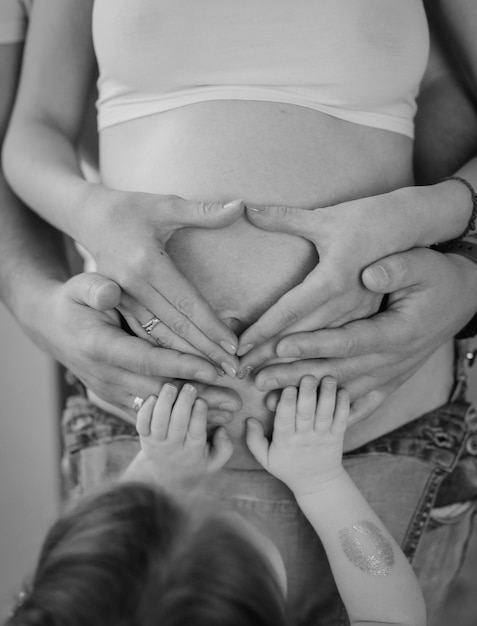 Foto mujer embarazada y su pequeña hija sosteniendo un corazón con las manos en el estómagoxa