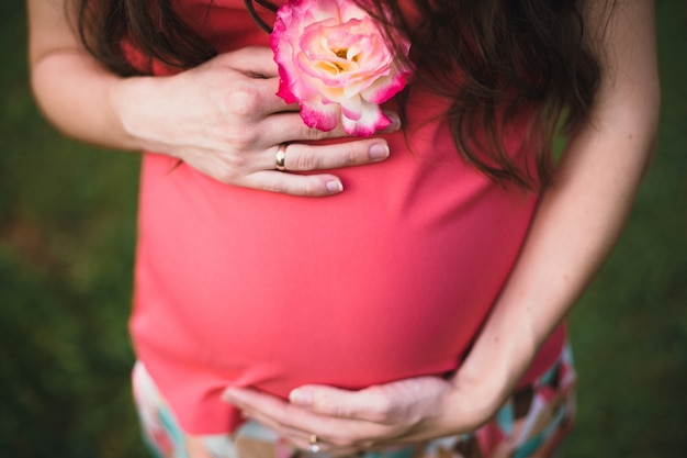 Foto mujer embarazada sujetando una flor blanca con los bordes rojos