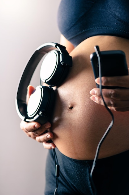 Mujer embarazada, tenencia, auriculares, en, ella, vientre