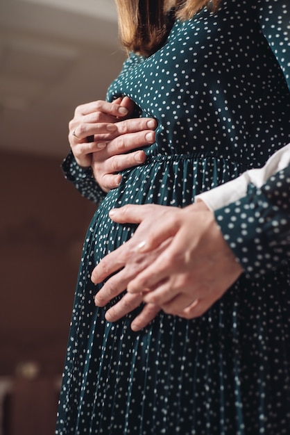 Una mujer embarazada tiene las manos de su marido sobre su vientre