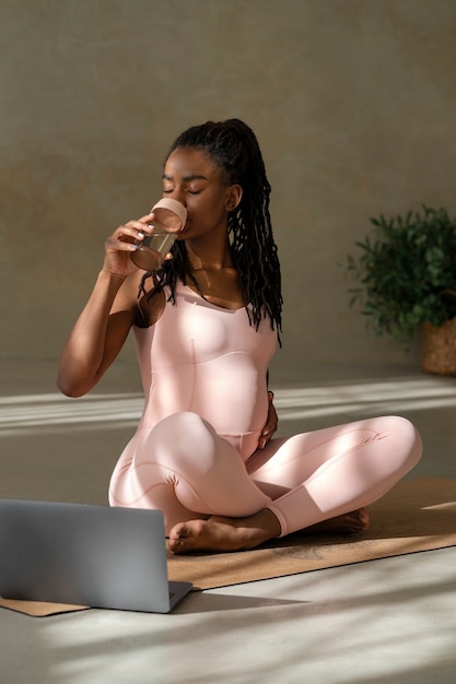 Foto mujer embarazada de tiro completo en estera de yoga