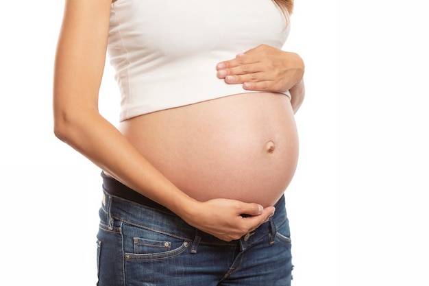 La mujer embarazada toca suavemente su gran barriga. Esperando un milagro. De cerca. Aislado