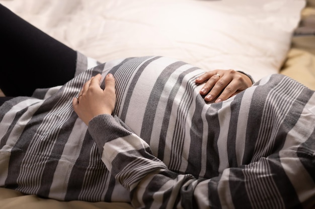 Mujer embarazada tocando su vientre en la cama Embarazo maternidad y expectativa